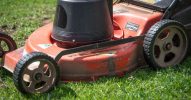 A close-up view of a red lawn mower on a green lawn, showcasing its details.